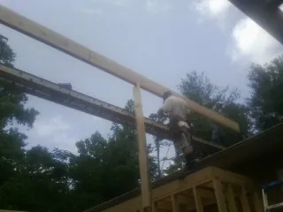 Carpenter setting a ridge beam over a new addition frame — Ice Dam Removal by Roofing Brothers in West College Corner