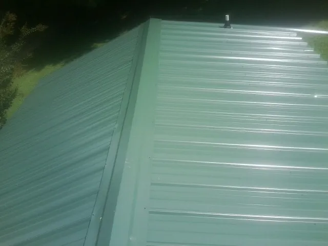 New green metal panels meeting at the ridge of a roof — Flat Roof Repair work by our crew in West College Corner