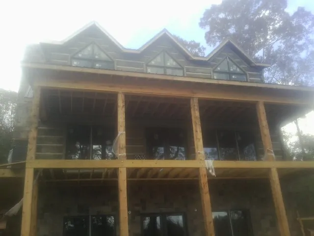 Dormers and porch framing on a large log home under construction — Roof Coating work by our crew in West College Corner