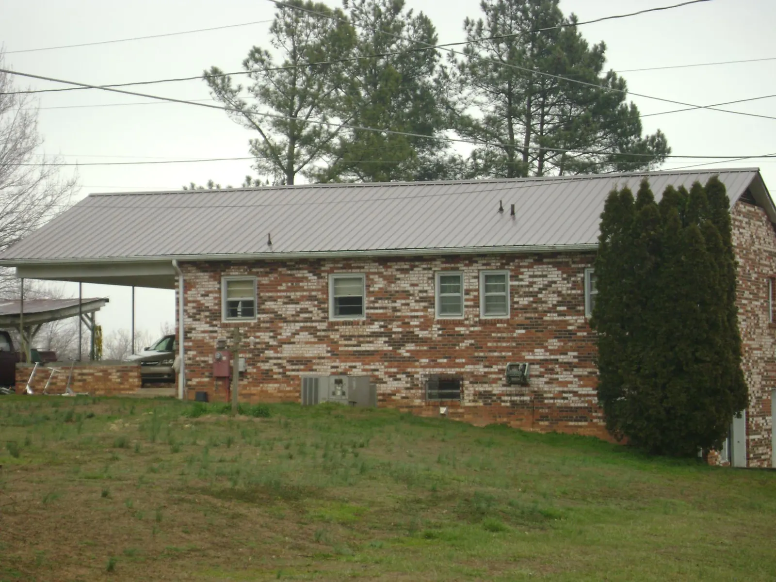 Gray metal roof on a brick split level home with a carport in West College Corner