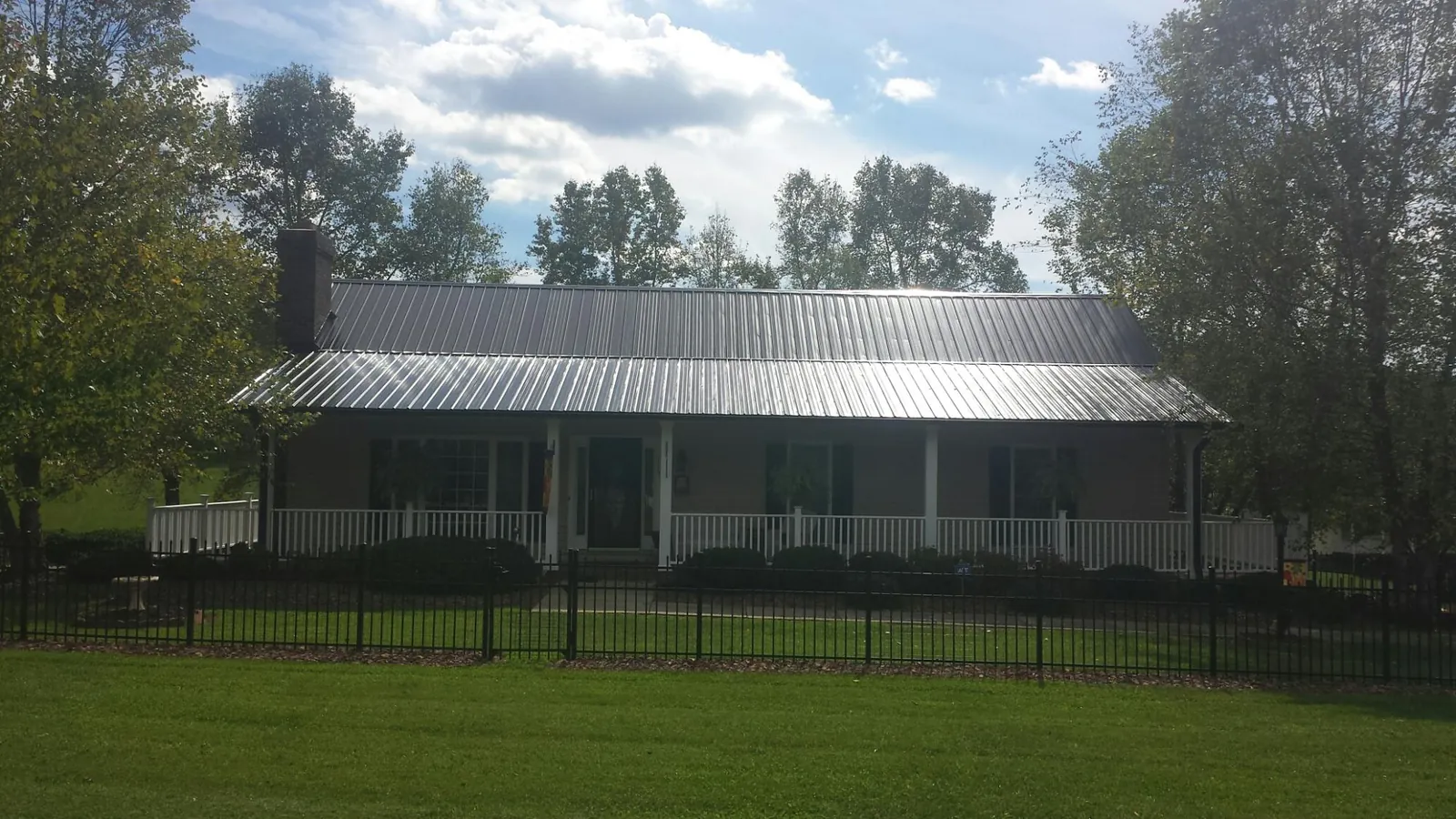 Gray metal roof on a brick ranch with a full width front porch — Gutter Guard Installation work by our crew in West College Corner