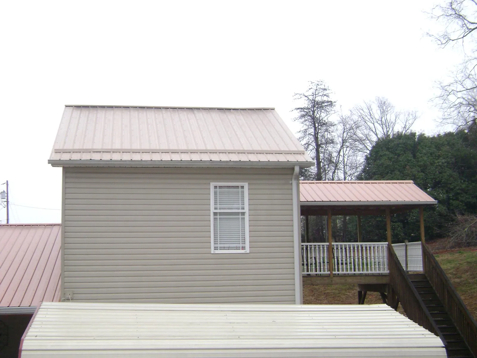 Tan metal roofs on a two story addition and attached porch, from a Roof Replacement job in West College Corner