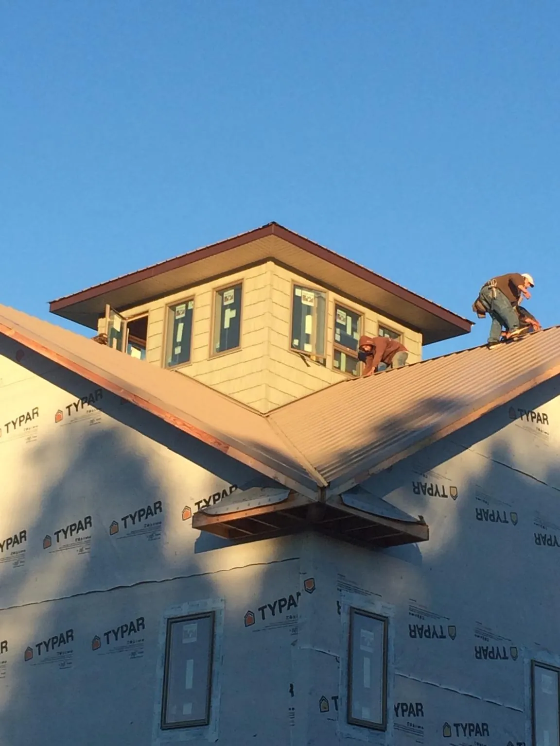 Roofers working around a rooftop cupola on a new metal roof at sunset — Roof Waterproofing in West College Corner by Roofing Brothers